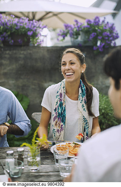 Glückliche Frau beim Mittagessen mit Freunden im Outdoor-Café