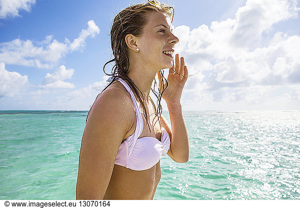 Glückliche Frau im Bikini-Oberteil vor bewölktem Himmel