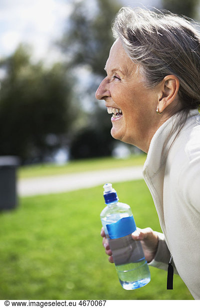 Glückliche Frau im Profil mit Wasserflasche