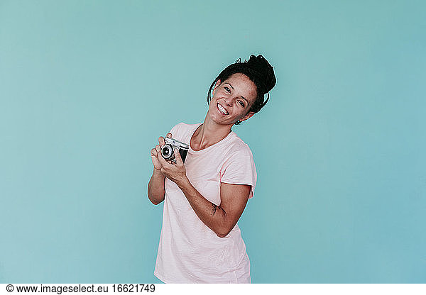 Glückliche Frau mit altmodischer Kamera vor türkisfarbenem Hintergrund