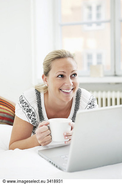 Glückliche Frau mit Computer und Kaffee