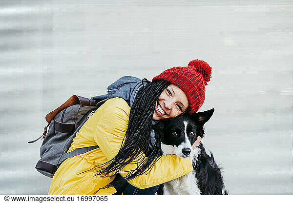 Glückliche Frau umarmt Haustier Hund gegen Wand