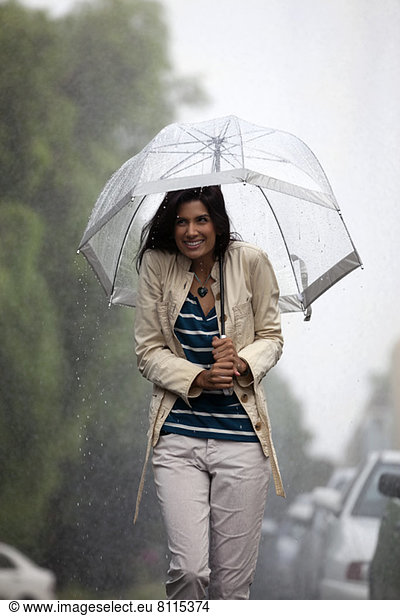 Glückliche Frau unter Schirm im Regen