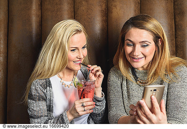 Glückliche Frauen mit Smartphone in der Kneipe