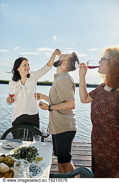 Glückliche Freunde beim Abendessen am See und beim Weintrinken