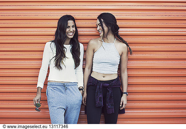 Glückliche Freunde in Sportkleidung stehen an oranger Wand