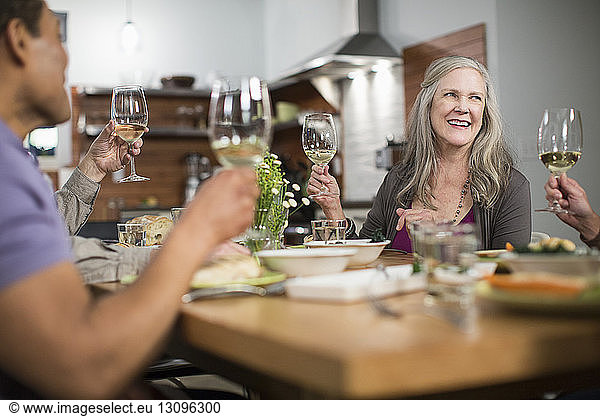 Glückliche Freunde mit Weingläsern sitzen bei geselligem Beisammensein am Tisch