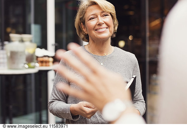 Glückliche Geschäftsfrau beim Anblick einer Kollegin vor dem Restaurant