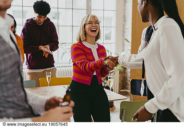 Glückliche Geschäftsfrau  die einer Kollegin während einer Veranstaltung im Kongresszentrum die Hand schüttelt