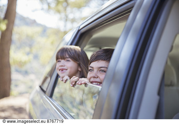 Glückliche Geschwister schauen aus dem Autofenster