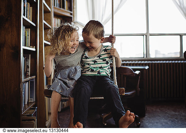 Glückliche Geschwister schwingen zu Hause an Bücherregalen vorbei
