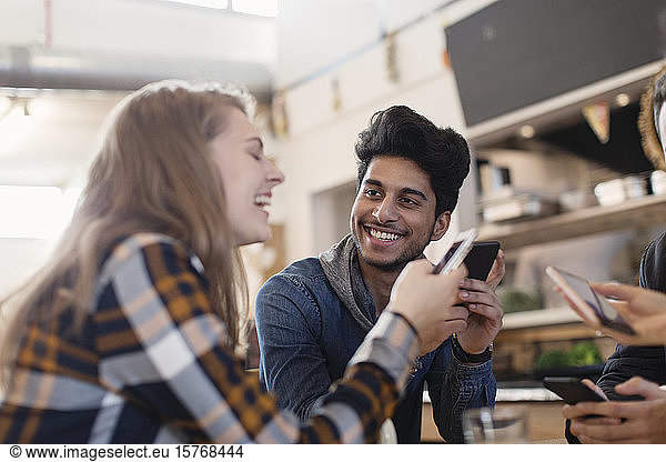 Glückliche junge Erwachsene  die im Café ihr Smartphone benutzen
