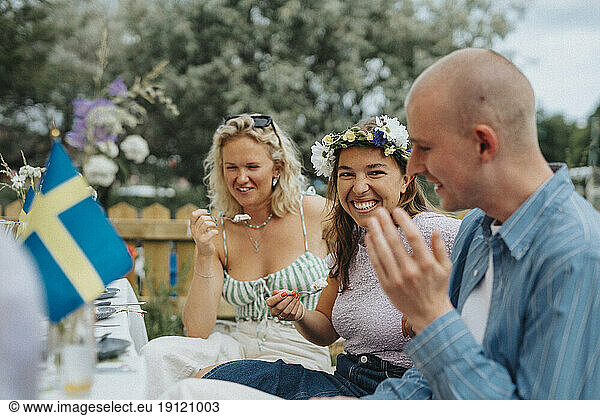 Glückliche junge Frau  die Kuchen isst  während sie sich mit Freunden bei einem Abendessen im Café vergnügt