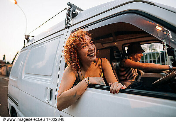 Glückliche junge Frau lehnt sich aus dem Fenster eines Lieferwagens