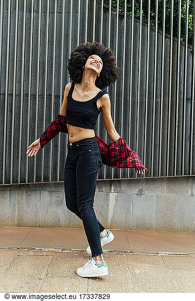 Glückliche junge Frau tanzt vor einer Wand