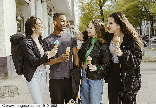 Glückliche junge Freunde essen Eis am Straßenrand