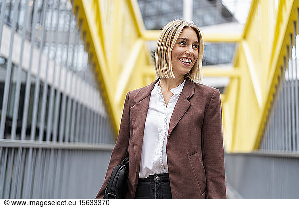 Glückliche junge Geschäftsfrau auf einer Brücke in der Stadt