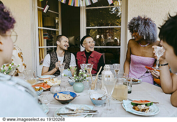 Glückliche LGBTQ-Freunde  die sich bei einer Dinnerparty im Hinterhof am Tisch unterhalten