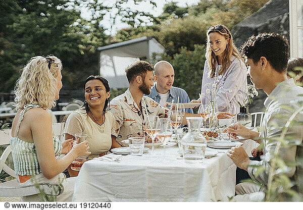 Glückliche männliche und weibliche Freunde  die das Essen genießen  während sie eine Dinnerparty im Café feiern