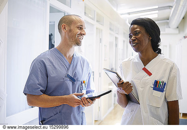 Glückliche Mediziner in Uniform diskutieren auf dem Krankenhauskorridor