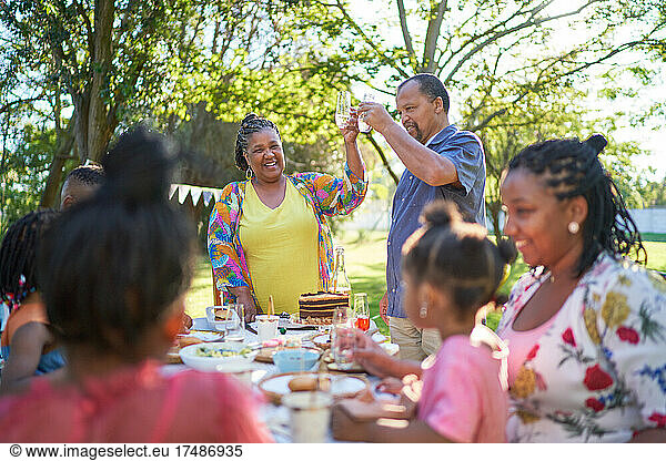 Glückliche Mehrgenerationen-Familie feiert Geburtstag im sommerlichen Hinterhof