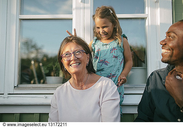 Glückliche Mehrgenerationen-Familie gegen Fenster an der Veranda