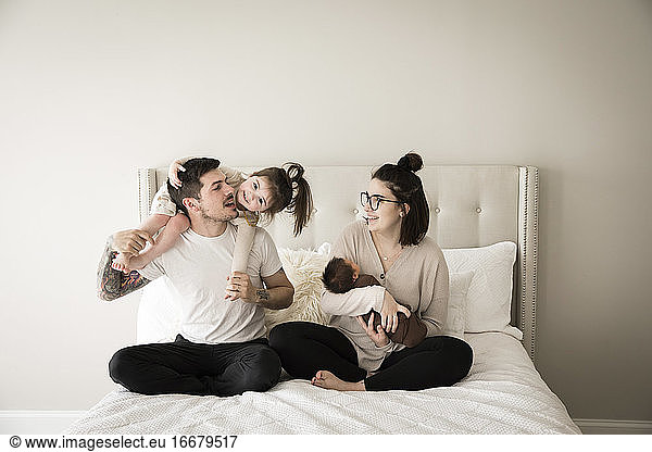 Glückliche Millennial-Familie spielt gemeinsam im Bett