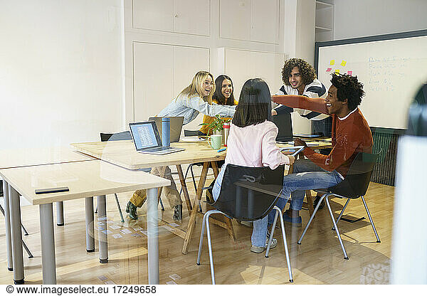 Glückliche multiethnische Geschäftskollegen am Konferenztisch im Büro