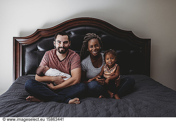 Glückliche multirassische Familie im Bett mit Vater und Kleinkind und Mutter und 2 Jahre alt