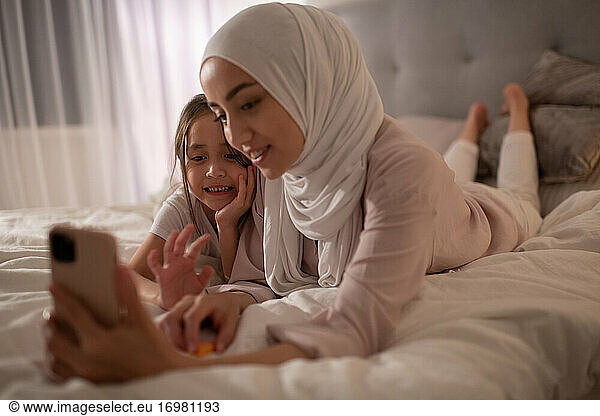 Glückliche muslimische Frau und Mädchen bei einem virtuellen Treffen