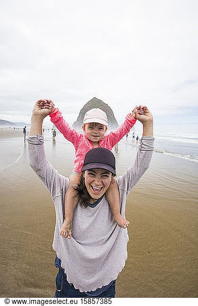 Glückliche Mutter lässt Tochter am Cannon Beach auf der Schulter reiten.