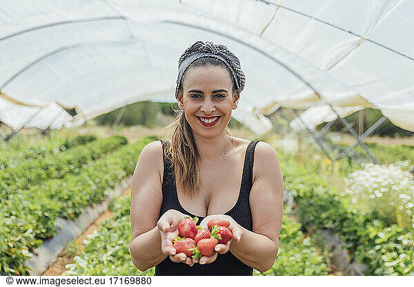 Glückliche schöne Bäuerin mit frischen Erdbeeren auf einem Bio-Bauernhof