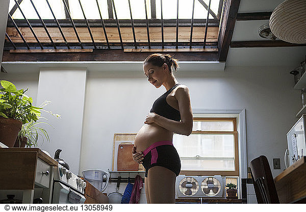 Glückliche schwangere Frau steht in der Küche