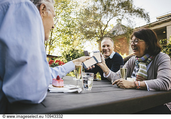 Glückliche Seniorenfreunde mit Mobiltelefonen im Outdoor-Café
