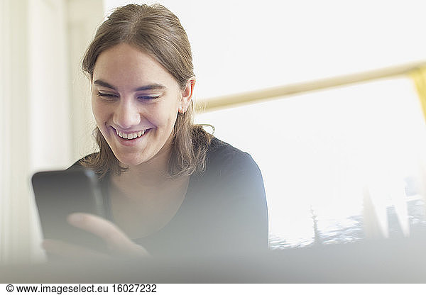 Glückliche Teenagerin benutzt Smartphone