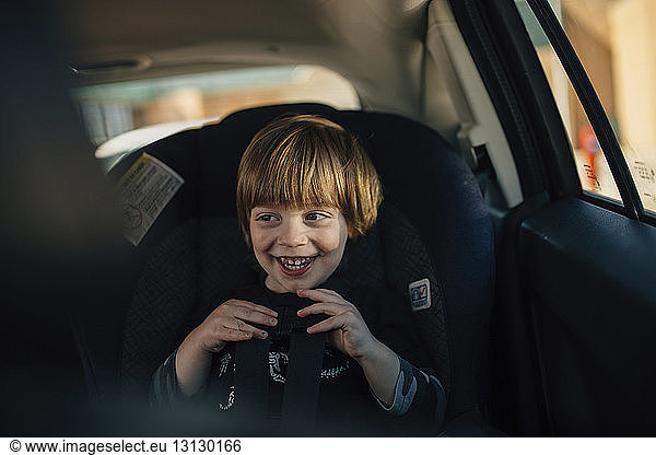 Glücklicher Junge schaut weg  während er im Auto sitzt