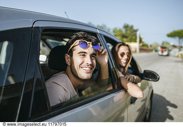 Glücklicher junger Mann und Frau in einem Auto mit Blick aus dem Fenster