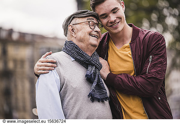 Glücklicher älterer Mann Kopf an Kopf mit seinem erwachsenen Enkel im Freien