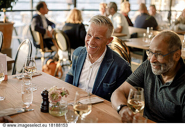 Glücklicher älterer Mann sitzt mit einem männlichen Freund im Restaurant