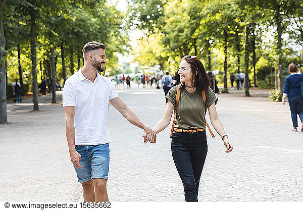 Glückliches junges Paar geht Hand in Hand in einem Park
