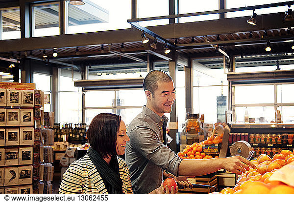 Glückliches junges Paar kauft Obst im Supermarkt