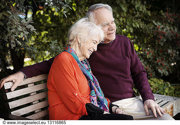 Glückliches älteres Ehepaar sitzt auf Parkbank