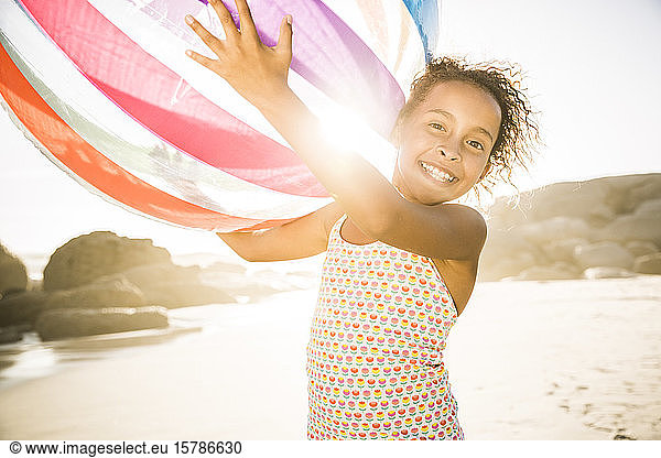 Glückliches Mädchen hält aufblasbaren Ball am Strand