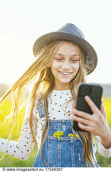 Glückliches Mädchen nimmt Selfie durch Smartphone auf landwirtschaftlichem Gebiet