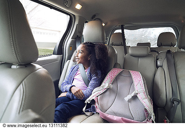 Glückliches Mädchen schaut durchs Fenster  während sie im Auto unterwegs ist