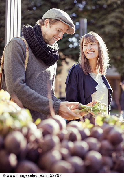 Glückliches Paar beim Gemüsekauf am Marktstand