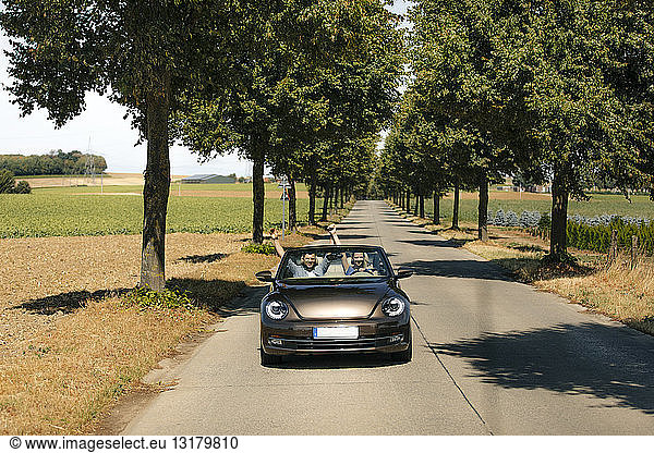 Glückliches Paar fährt in einem Cabriolet auf einer Landstraße