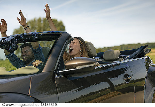 Glückliches Paar fährt mit einem Cabriolet auf einer Landstraße
