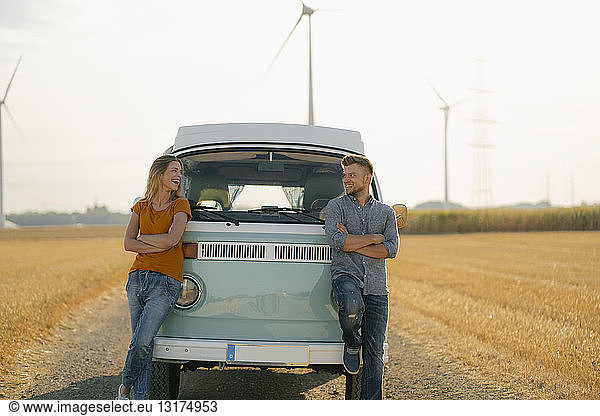 Glückliches Paar im Wohnmobil in ländlicher Landschaft mit Windturbinen im Hintergrund