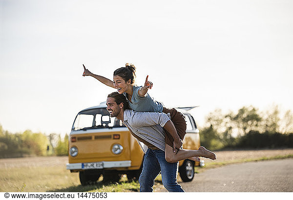 Glückliches Paar macht eine Autoreise mit einem Wohnmobil und gibt vor  auf der Straße zu fliegen